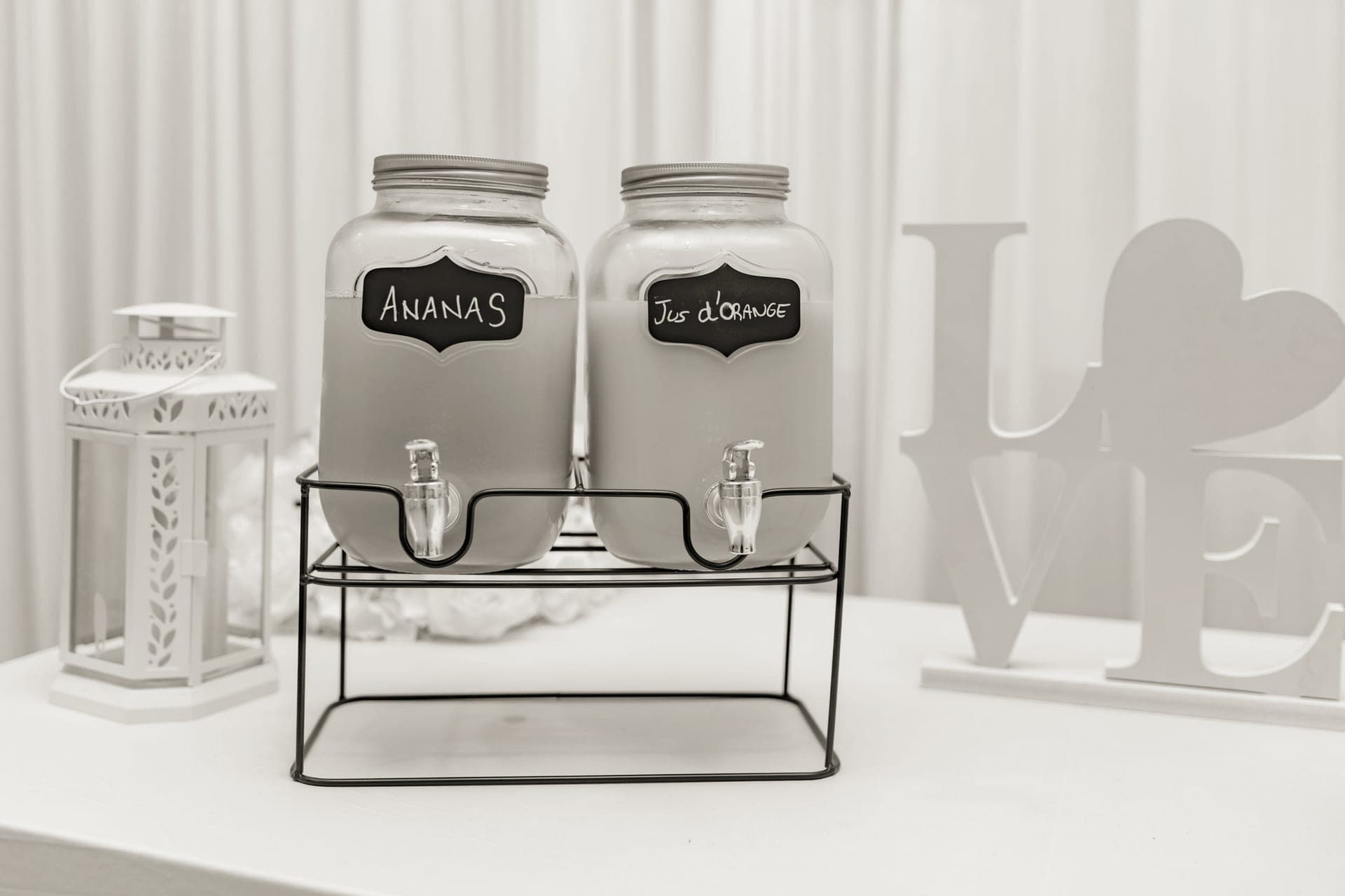 A glass drink dispenser of lemonade with a spigot on a party table