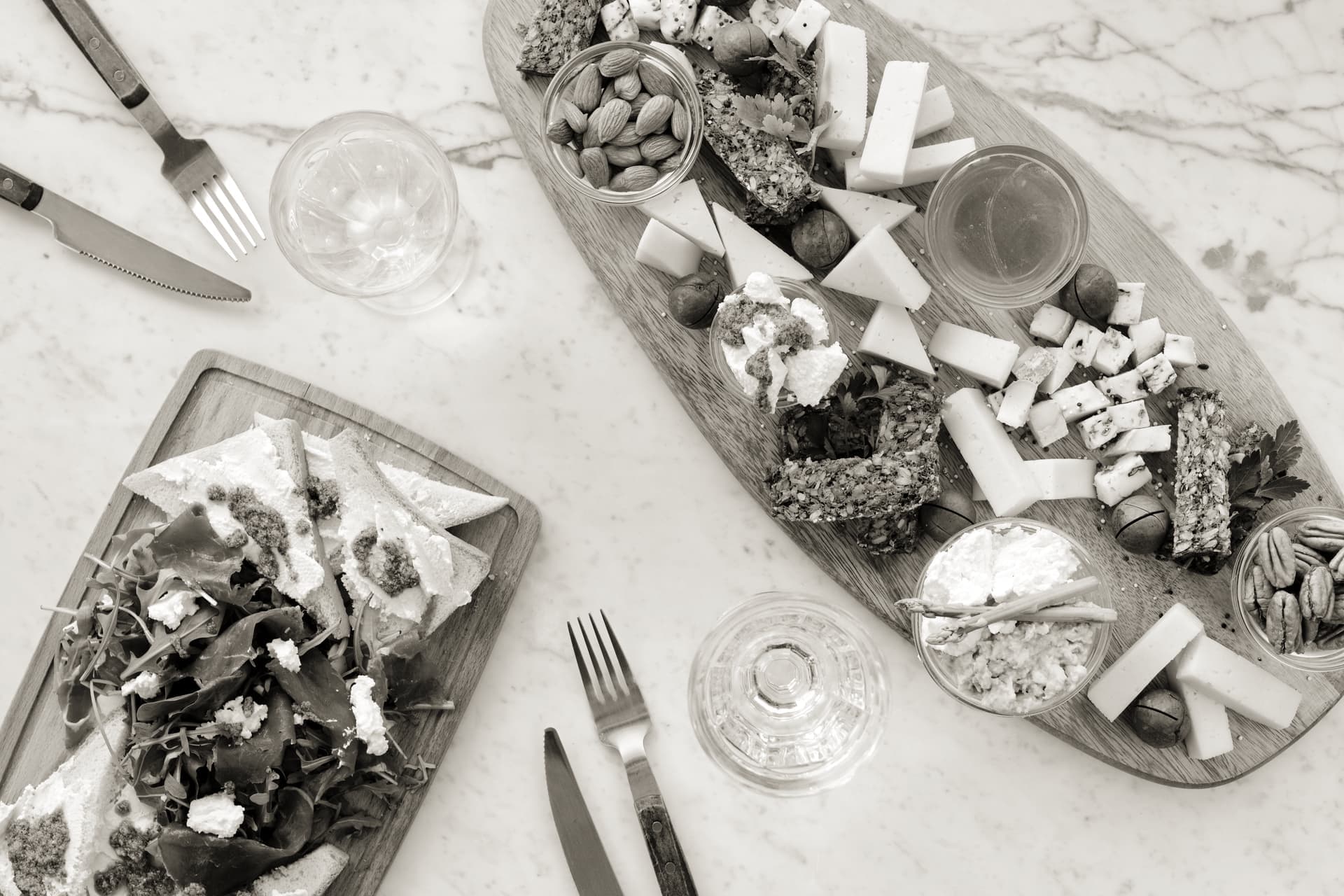 Cheese knives and small bowls set out beside a loaded charcuterie board