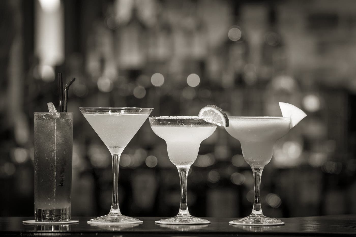 Cocktail glasses filled with mixed drinks on a bar top
