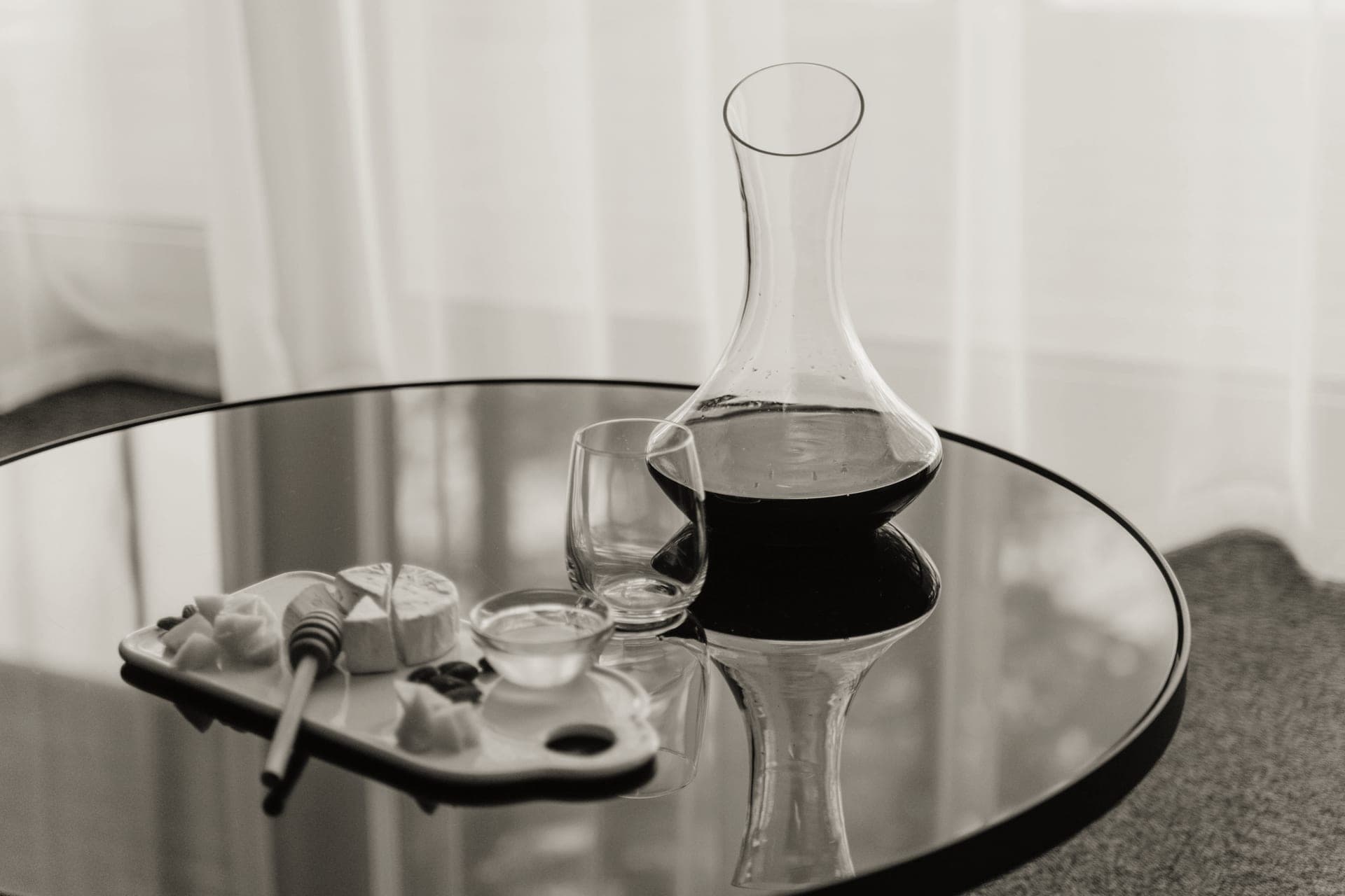 A glass decanter of red wine standing beside a filled glass