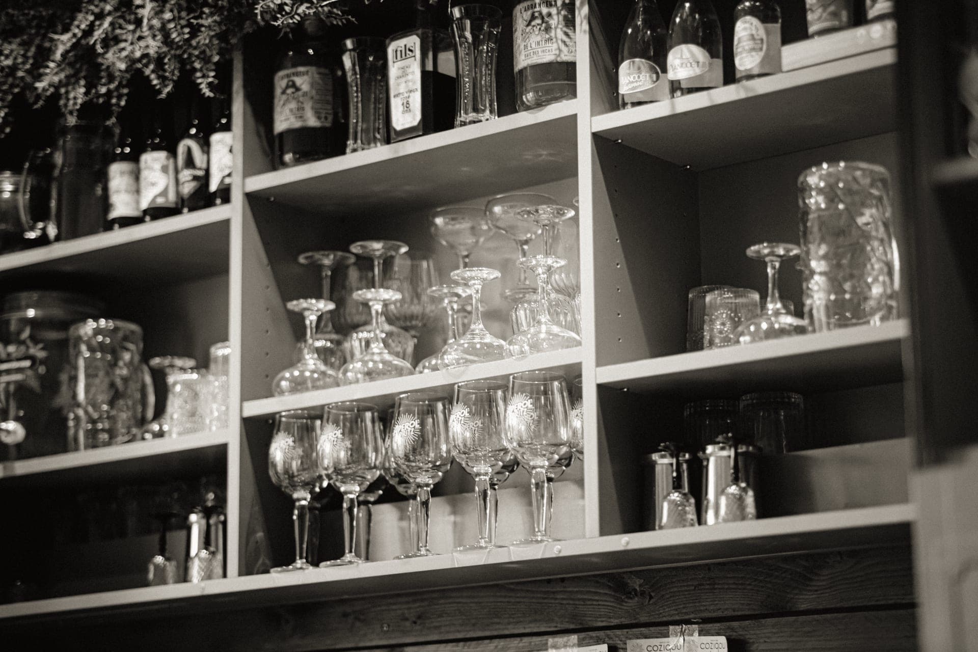 Assorted drinking glasses and wine glasses lined up on a shelf