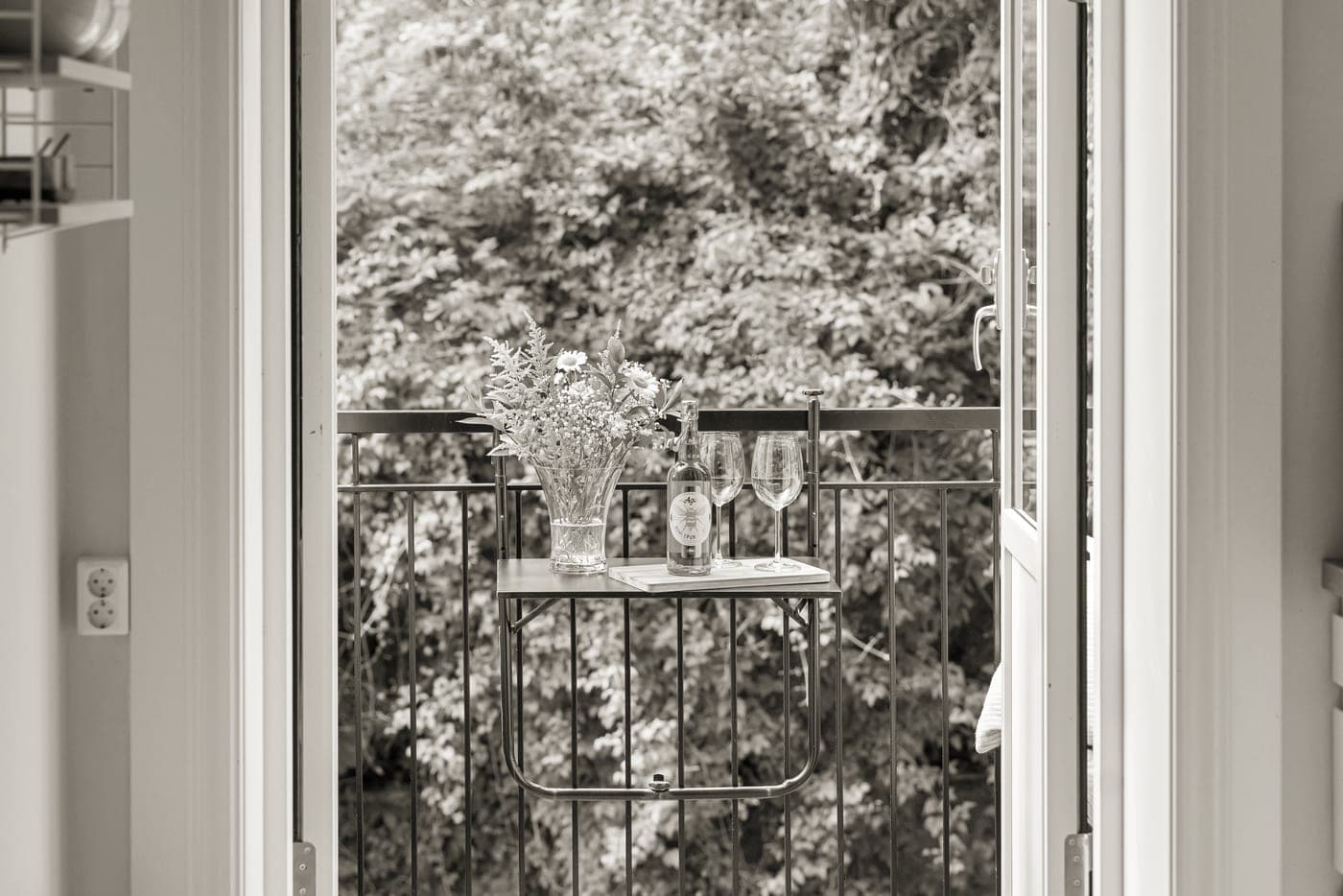A hostess gift of a bottle and flowers being handed over at a door