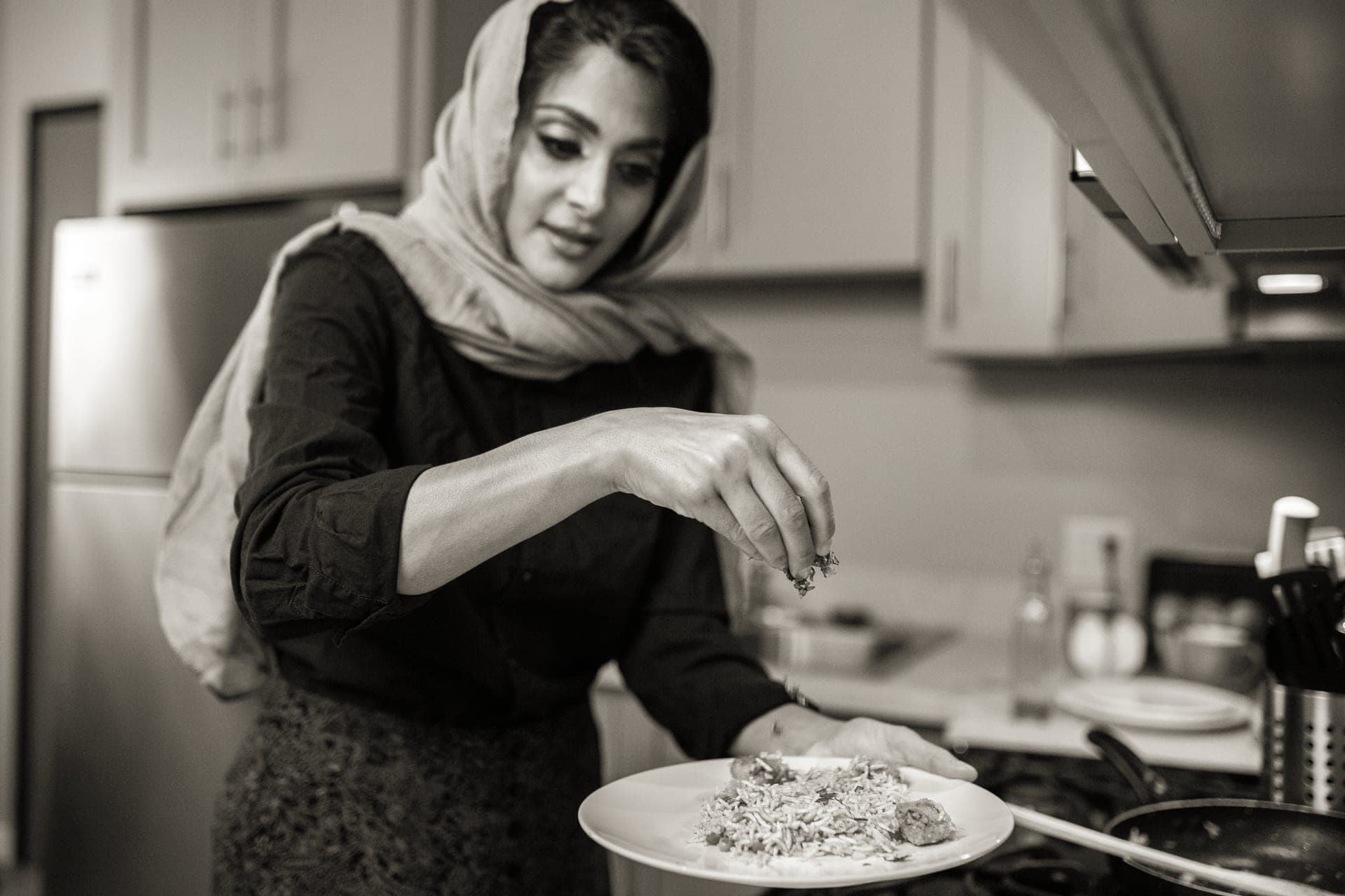 A home cook plating food at a kitchen counter
