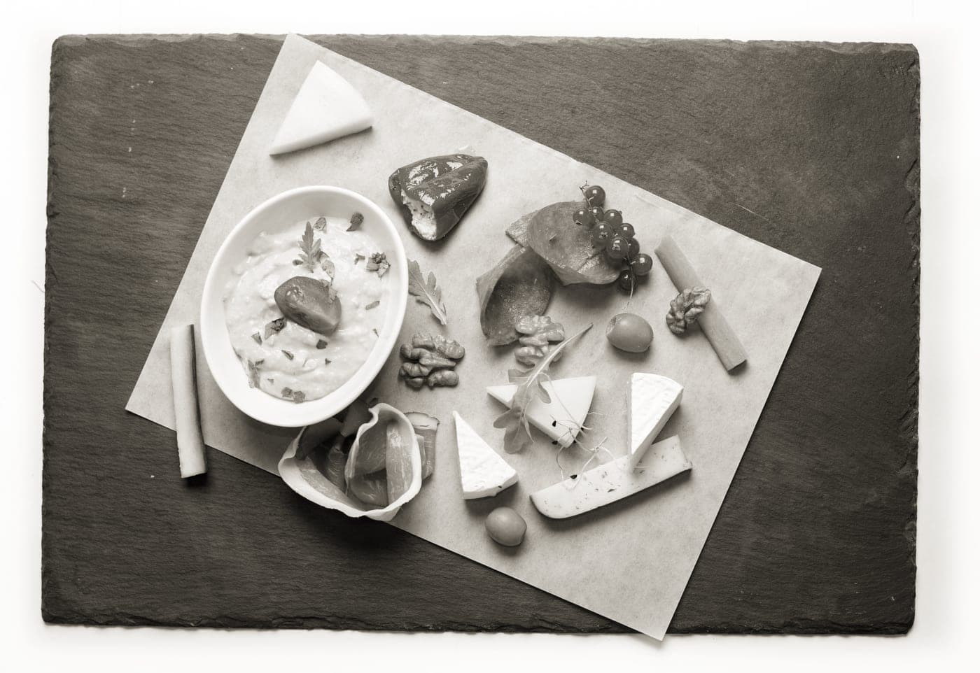 A marble serving board holding cheese beside a dark slate board