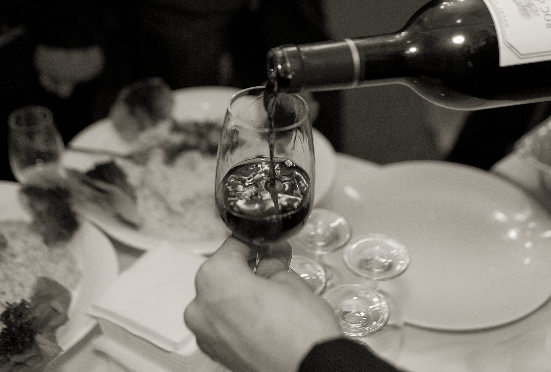 Red wine being poured into a large-bowled wine glass
