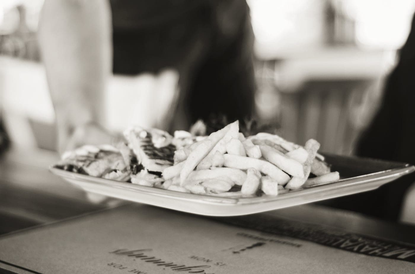 A serving tray being carried to a table with food on it