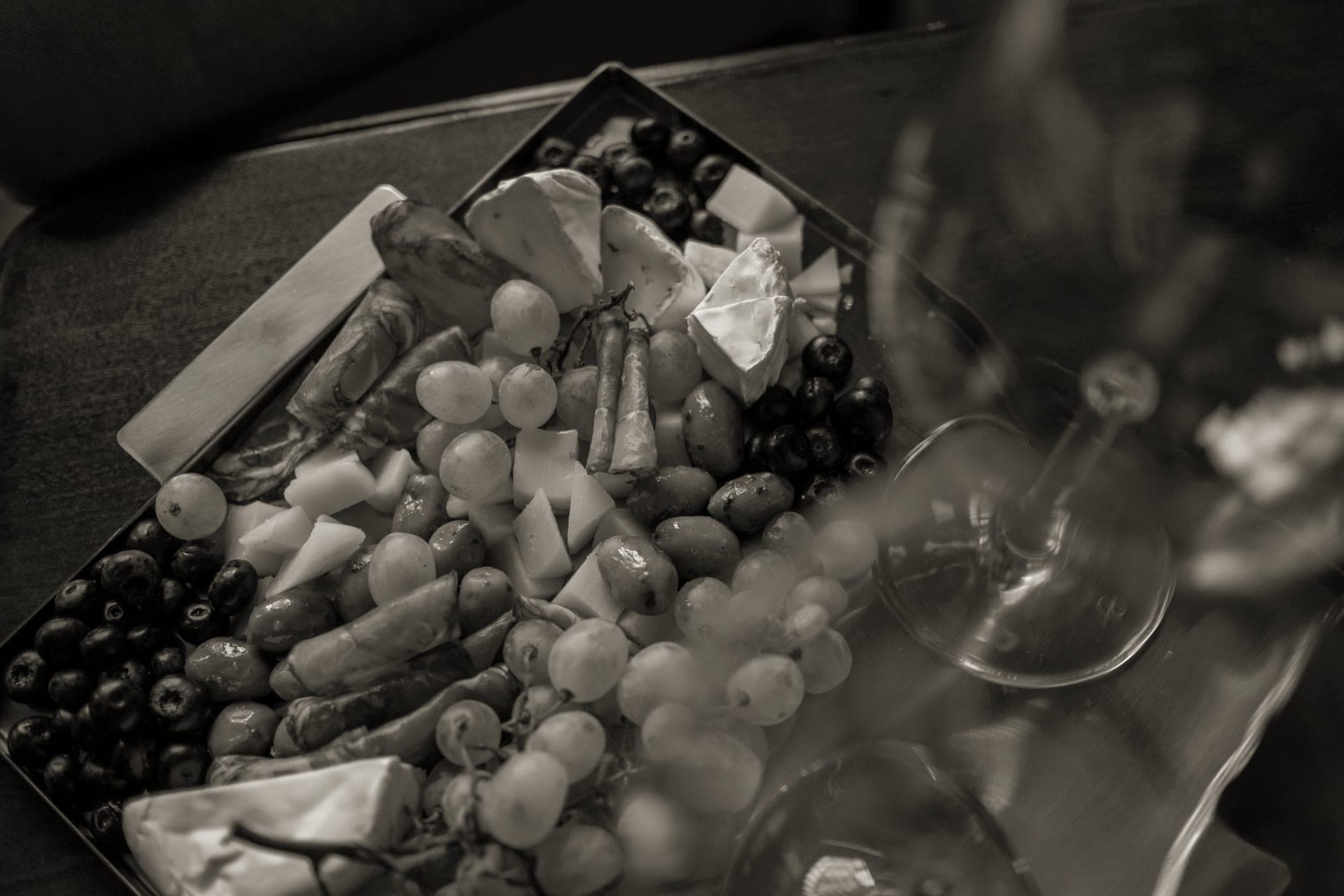 A small wooden board with cheese and grapes set out for two