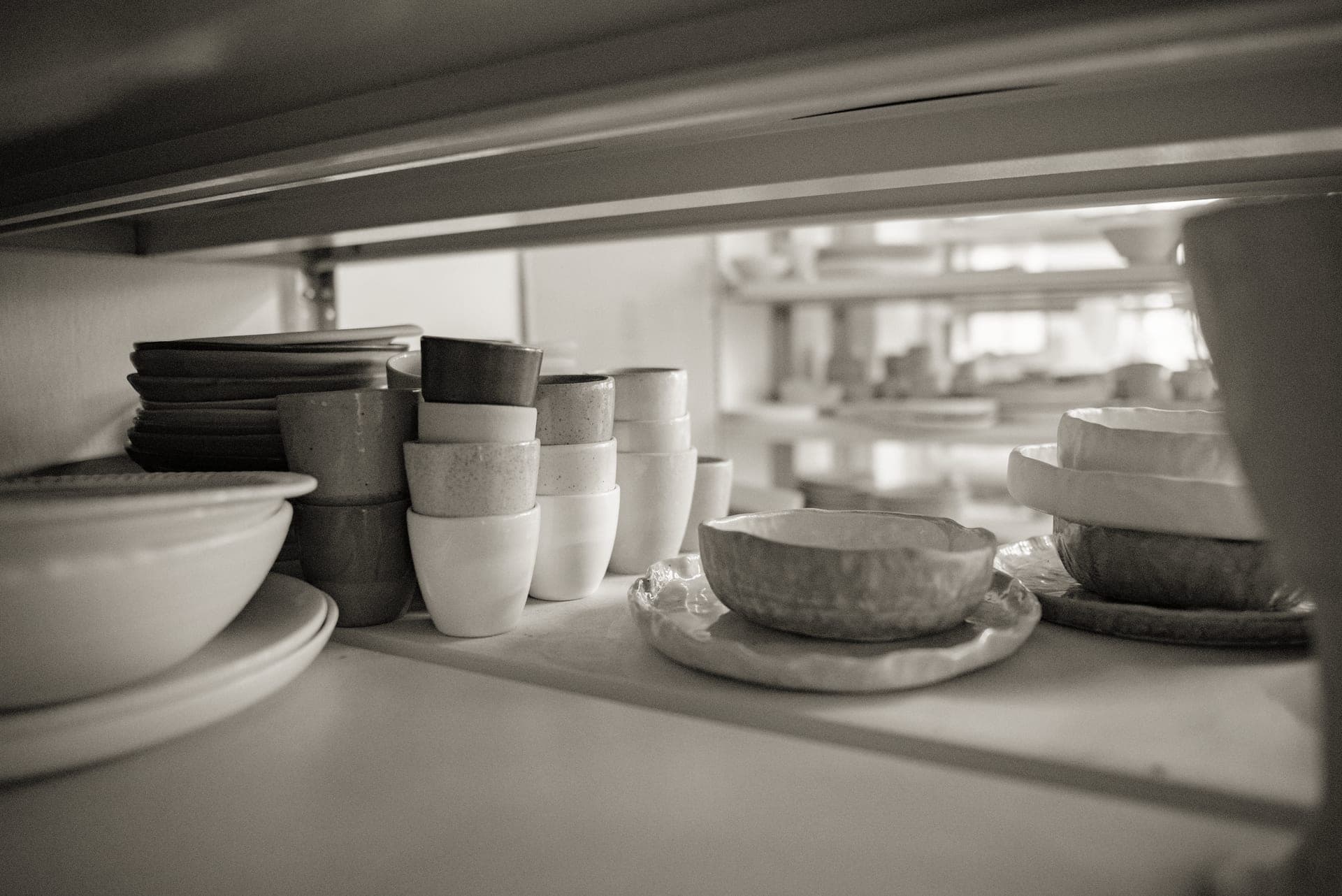 Stoneware plates and bowls stacked on a kitchen shelf