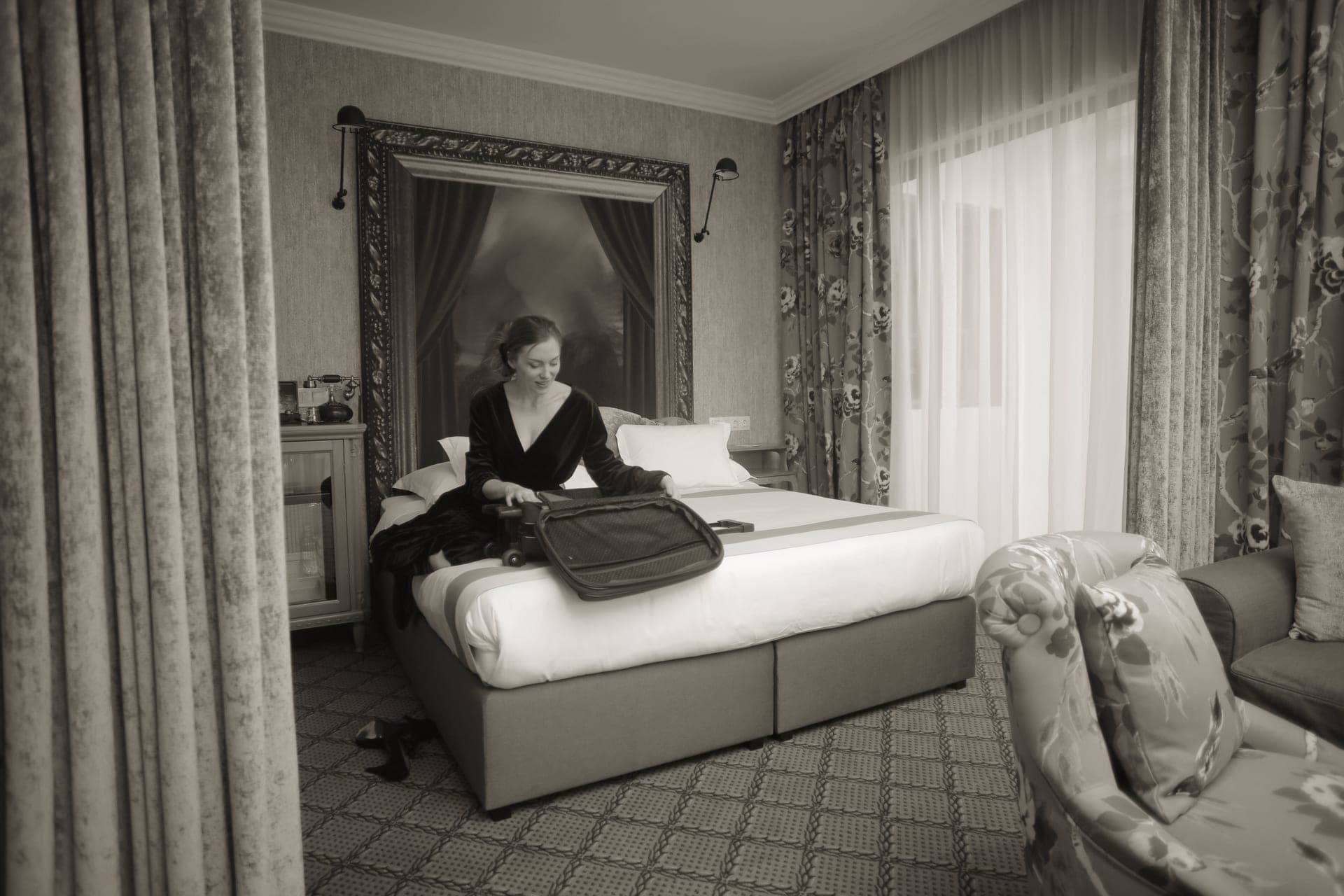 A guest bedroom with an overnight bag and flowers on the dresser
