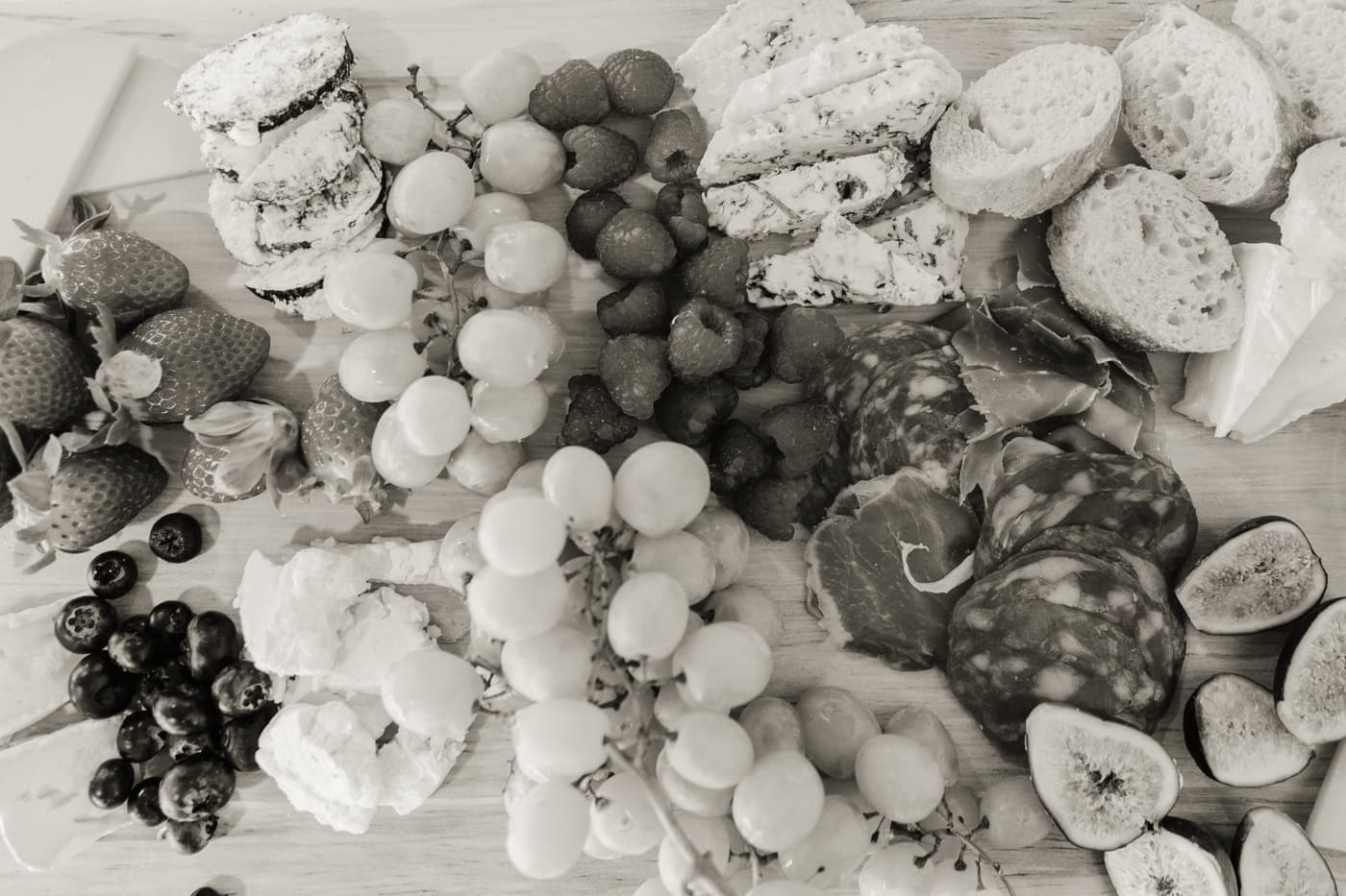 Assorted cheeses, cured meats and fruit laid out flat before assembly